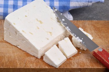 Kesme tahtasına yakın plan bıçaklı bir peynir parçası.