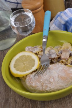 Mantar soslu tavuk göğsü makarna ve bir dilim limon yakın çekim tabağında servis edilir.