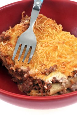 Beyaz arka planda çatalla yakın plan servis edilen bir tabak lazanya.