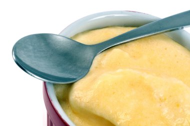 Limon kremalı ramekin, kaşıklı ve limonlu beyaz arka planda.