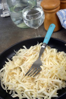 Bir bardak suyla servis edilen rendelenmiş kereviz tabağı.