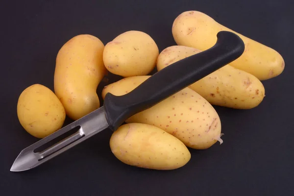 Patatas Con Pelador Verduras Cerca Sobre Fondo Negro — Foto de Stock