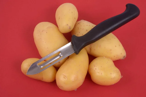 Batatas Com Descascador Vegetal Close Fundo Vermelho — Fotografia de Stock