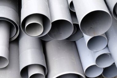 Farklı boyutlarda gri plastik borular istiflenmiş