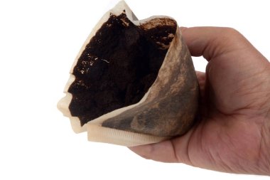 Someone with coffee grounds in a paper filter in hands close-up on white background 