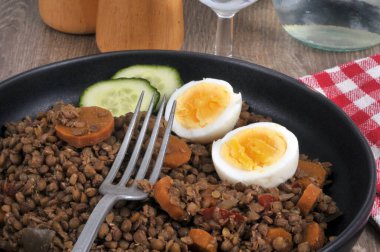 Dilimlenmiş havuç, salatalık ve yakın plan çatalla servis edilen haşlanmış yumurtayla mercimek.