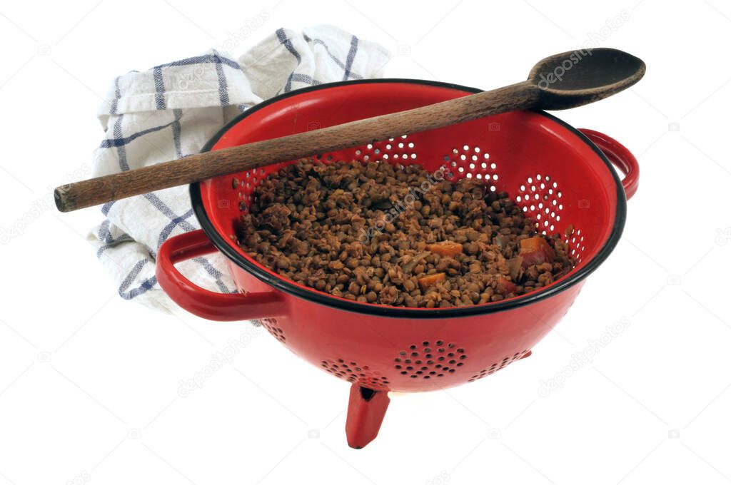 Lentil colander with wooden spoon and kitchen towel close-up on white background