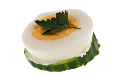Bir dilim salatalıkla aperatif ve beyaz arka planda bir dilim haşlanmış yumurta. 