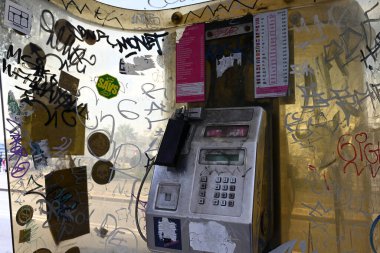 Grafiti ve çıkartmalarla kaplı Split 'te bir telefon kulübesinde eski bir telefon.