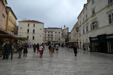 Turistler, arka planda saat kulesiyle Split 'in Narodni Meydanı' nda geziniyorlar. 