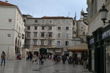 Turistler, arka planda saat kulesiyle Split 'in Narodni Meydanı' nda geziniyorlar.