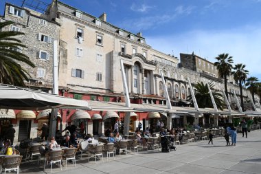 Güneşli bir günde, Riva 'daki barların ve restoranların teraslarında masalarda oturan turistler
