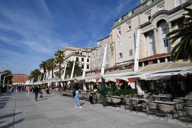 Güneşli bir günde, Riva 'daki barların ve restoranların teraslarında masalarda oturan turistler