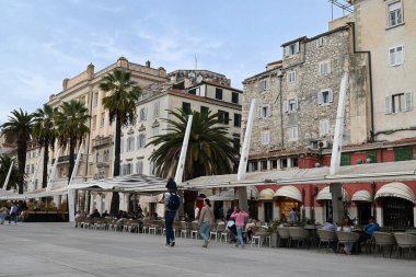Turistler, Split 'teki Riva' daki bar ve restoranların teraslarında masalarda oturuyorlar.