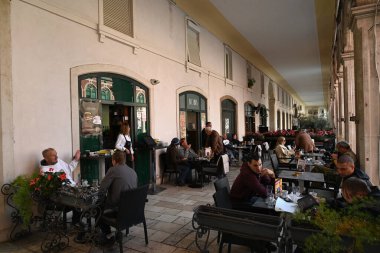 Müşteriler, Split 'teki Cumhuriyet Meydanı' nın atari salonlarının altındaki bir bar restoranının terasında masalarda oturuyordu. 