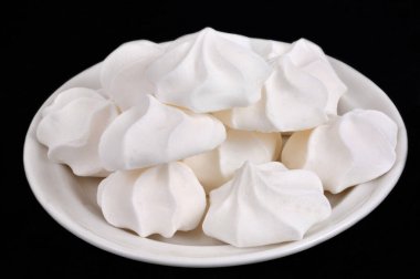 Siyah arka planda izole edilmiş, yakın planda bir tabağa yerleştirilmiş kremalar.