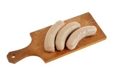 Beyaz arka planda izole edilmiş, tahta kesme tahtasındaki beyaz sosislerin yakın çekimi.