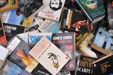 Çeşitli yayıncılardan gelen Fransızca karton kapaklı kitaplar arka planda birikmiş