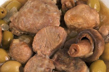 Arka planda zeytin ve mantarlı dana eti yakın plan.