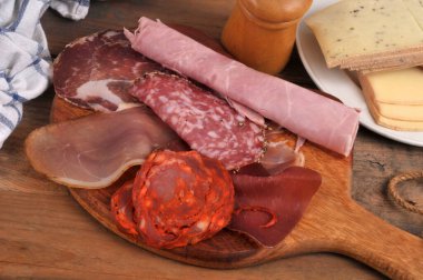 Ahşap kesim tahtasında bir tabak raket peyniri ile pişirilmiş et çeşitleri.