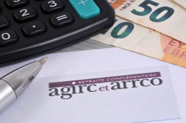 Yakın planda kalem, hesap makinesi ve avro banknotlarıyla birlikte Agirc-Arrco tamamlayıcı emeklilik başvuru formu