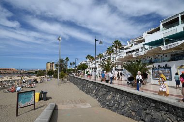 Turistler Tenerife 'deki Las Vistas plajının yanında geziniyorlar