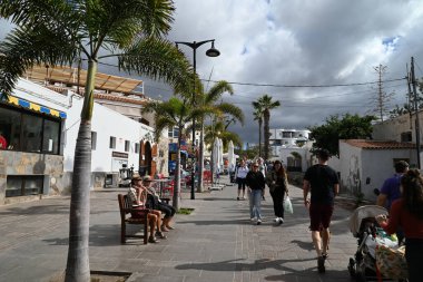 Turistler Tenerife adasındaki Paseo Maritimo de Los Cristianos 'ta geziniyorlar.