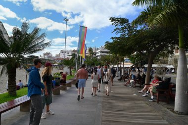 Turistler Tenerife adasındaki Paseo Maritimo de Los Cristianos 'ta geziniyorlar.
