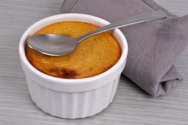 Bir kaşık ve peçeteyle ev yapımı karamelli pasta ramekin, ahşap arka planda yakın plan gösterilir.