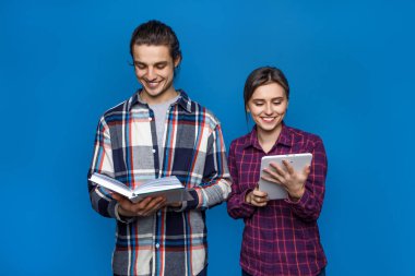 Mavi arka planda dizüstü bilgisayarı, kitapları ve defterleri elinde tutan birkaç genç öğrenci. İki üniversite öğrencisi öğretmenlik yapıyor..