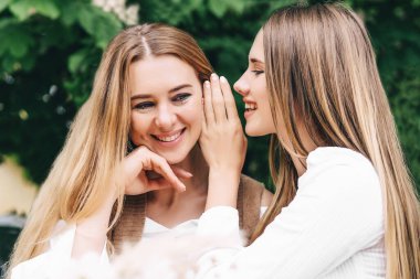 Sarışın anne ve kızı kulağına bir şey söylüyor..