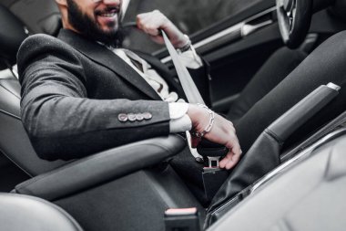 Erkek eli arabanın emniyet kemerini bağlar. Araba sürmeden önce emniyet kemerinizi bağlayın ve güvenli bir yolculuğa çıkın. Erkek sürücünün yakın çekimi emniyet kemerini bağlıyor.