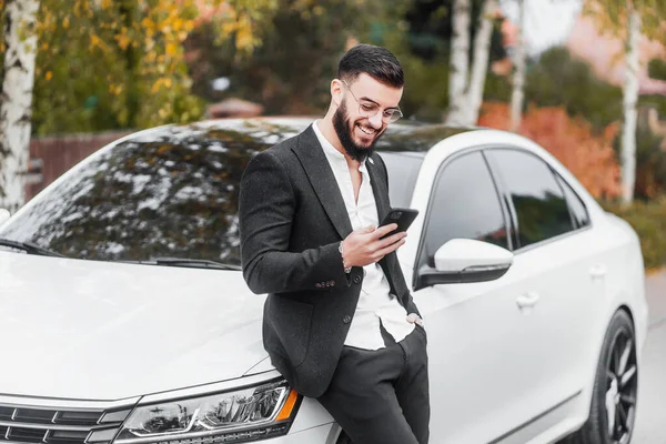 Erfolgreicher Geschäftsmann Blickt Auf Das Telefon Mit Einem Lächeln Auf — Stockfoto
