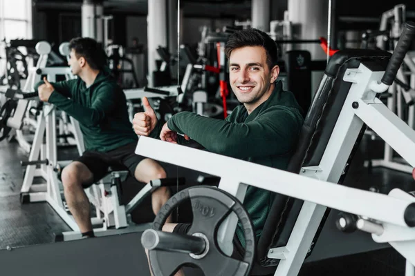 Der Junge Trainer Fitnessstudio Blickt Lächelnd Die Kamera Und Zeigt — Stockfoto