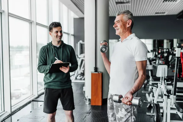 Der Senior Trainiert Mit Hanteln Der Trainer Beobachtet Und Protokolliert — Stockfoto