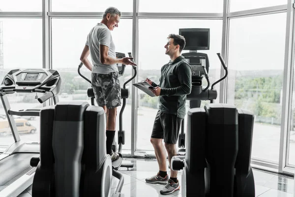 Homem Sênior Exercita Orbitrek Ouve Conselho Seu Treinador Fitness — Fotografia de Stock