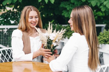 Şaşırmış anne kızından çiçek kabul eder. Anneler Günü. Kadınlar Günü.