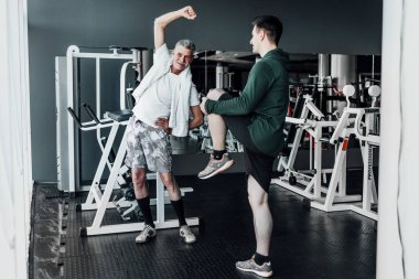 Spor salonunda iki adam antrenmandan önce kaslarını ısıtıyor. Hayatın sporu..