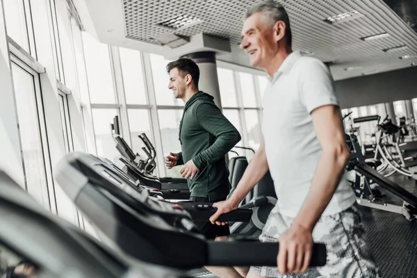 Sport. Portrait of two men running on a jogging track in a gym.