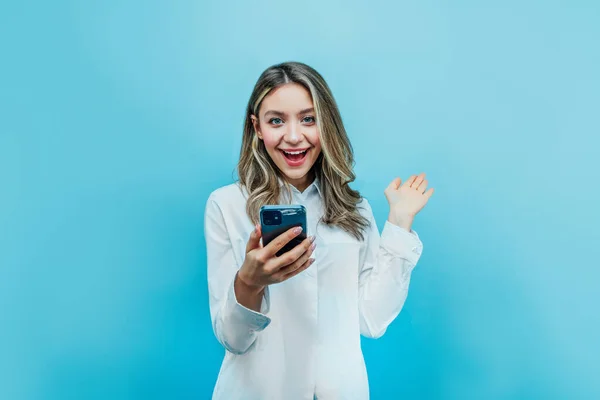 Chica Encantadora Sobre Fondo Azul Sostiene Teléfono Mano Mira Cámara — Foto de Stock