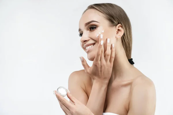 Fundo Branco Uma Mulher Que Aplica Creme Seu Rosto Radiante — Fotografia de Stock