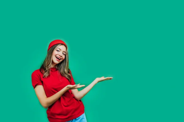 绿色背景 穿着红色衣服的漂亮姑娘 背景是绿色的 有文字的空间 她向自由自在的空间方向伸出她的手 复制的地方 案文的位置 — 图库照片