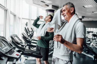 Odaklanırsak, son sınıftan bir adam spor salonunda su içip havluyla sildikten sonra poinin arkasında bulanık bir adam buluyor. Spor yaşam tarzı. Spor salonu, antrenman..