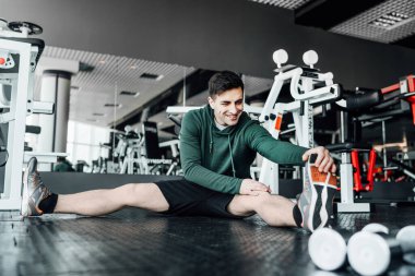 Spor salonundaki çekici adam antrenmandan önce esniyor. Spor salonundaki yakışıklı adam..