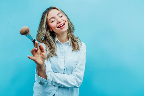 Artista Maquiagem Menina Fundo Azul Ela Está Sorrindo Segurando Uma — Fotografia de Stock