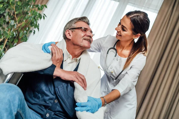 Una Enfermera Sonriente Con Estetoscopio Alrededor Cuello Envuelve Hombre Mayor — Foto de Stock