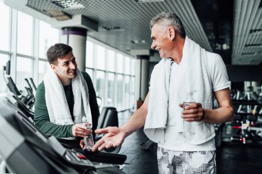 Spor salonundaki bir antrenmanın ortasında konuşan iki adamın portresi. Kardiyo. Spor. Spor salonunda iki arkadaş..