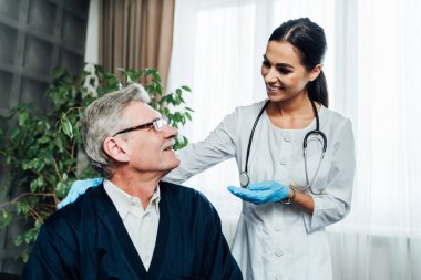 Kadın bir doktor hasta büyükbabasıyla iletişim kurar. Aile doktorunun konsültasyonu. Evde tedavi.