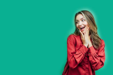 Yazı için yeri olan yeşil bir arka planda mutlu bir şekilde şaşırmış tatlı kız yazının içeriğiyle birlikte yana bakıyor..