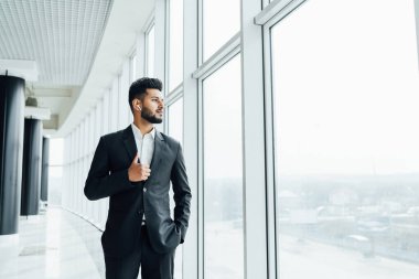 Pencerenin yanında duran yakışıklı, sakallı, siyah takım elbiseli, patron, şirket çalışanı, ofis çalışanı..